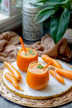 two glasses of carrot juice on a plate