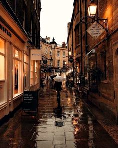 a person walking down a wet street in the rain with an umbrella over their head