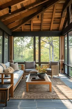 a living room filled with lots of furniture under a wooden roof over looking a forest