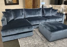 a blue sectional couch and ottoman in a living room with rugs on the floor