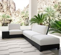 a white and black couch sitting on top of a floor next to a palm tree