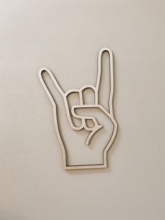 a metal peace sign hanging on the side of a white wall with one hand up in the air