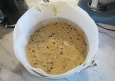 a white bowl filled with batter sitting on top of a counter next to an electric blender