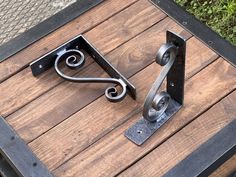 two metal brackets on top of a wooden table