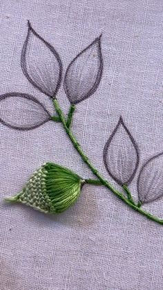 a close up of a piece of cloth with leaves on it and thread in the middle