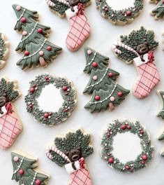 decorated christmas cookies arranged on a table with wreaths and trees in the middle,