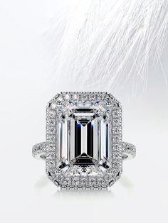 an emerald - cut diamond surrounded by white feathers is featured in this engagement ring photo