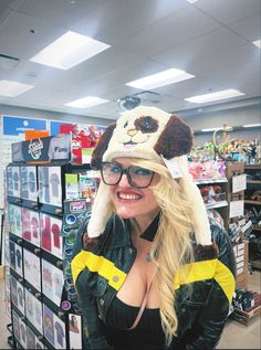 a woman wearing a hat with a stuffed animal on it's head in a store