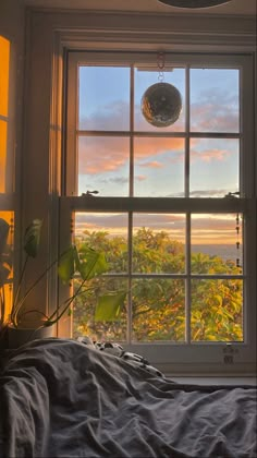 a bedroom with a window that looks out onto the trees outside and sunset in the distance