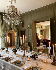 a dining room table set with place settings and candles on the tables in front of it