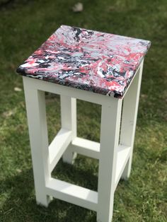 a small white stool sitting on top of a grass covered field