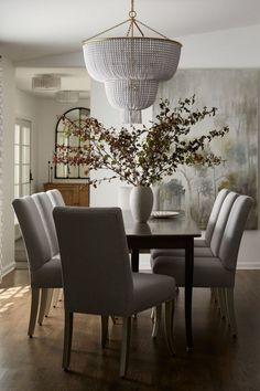 a dining room table with chairs and a chandelier hanging from it's ceiling