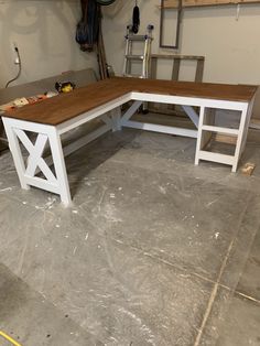 a white and wood table in a garage with tools on the floor next to it