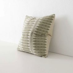 a white and green pillow sitting on top of a table next to a white wall