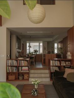 a living room filled with furniture and bookshelves next to a dining room table