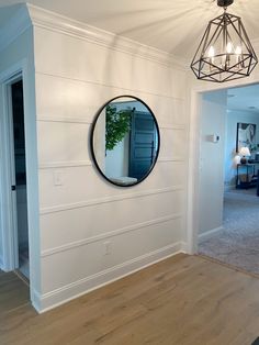 a mirror on the wall in a room with wood flooring and white painted walls