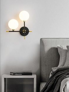 a bedroom with a bed, nightstand and two lights on the wall above it in black and white