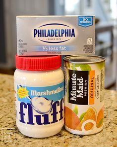 two jars of yogurt and a carton of oranges on a counter