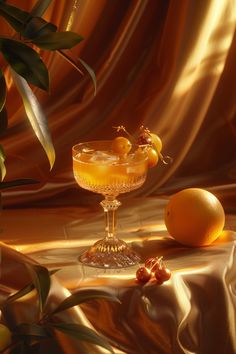 two oranges are sitting on a table next to a glass with an alcoholic drink in it