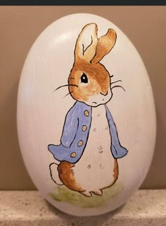 a painted easter egg with an image of a rabbit wearing a blue jacket on it