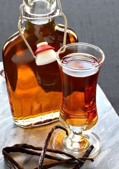 a bottle of syrup next to a glass filled with an apple cider and cinnamon sticks