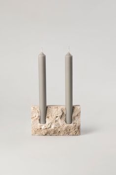 two candles sitting on top of a stone block