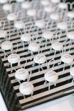 small white buttons with names on them are sitting on a black and white striped table