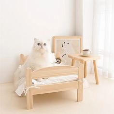 a white cat sitting on top of a wooden bed