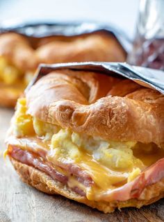 a close up of a bagel sandwich with eggs and ham in it on a table