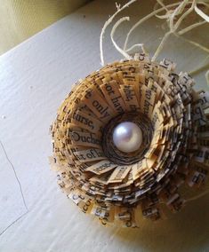 an ornament made out of old book pages with a pearl in the center