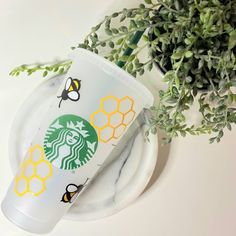 a starbucks cup sitting on top of a plate next to a plant