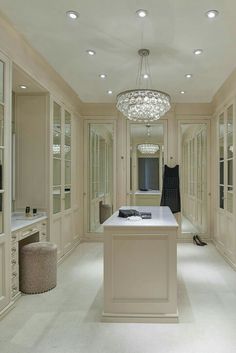 a large white kitchen with an island and chandelier hanging from the ceiling above it