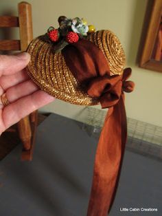 a hand holding a straw hat with flowers on it