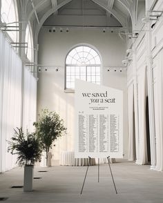 a large white sign in an empty building with flowers on the floor and windows above it