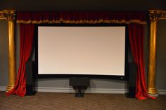 a large screen in the middle of a room with red drapes and gold pillars