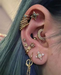 a woman with green hair wearing gold ear piercings and earrings on her ears,