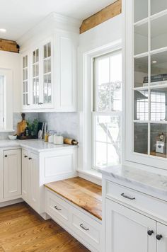 a kitchen with white cabinets and wood floors