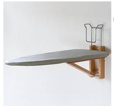 a ironing board mounted on a wall with a wooden holder attached to the side