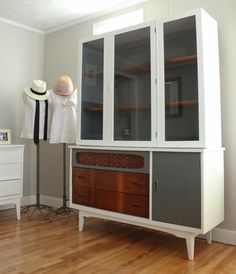 a white and grey cabinet sitting on top of a hard wood floor next to a hat rack