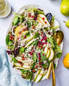 a white plate topped with salad next to pears