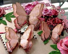 three butterflies are sitting on top of a table cloth with flowers and beads around them