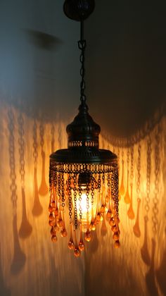 a chandelier hanging from the ceiling in front of a wall with curtains behind it