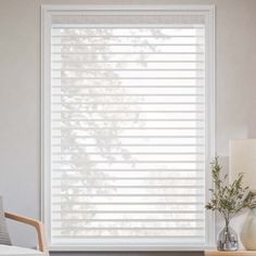 a bedroom with white blinds in the window and a nightstand on the side table next to it