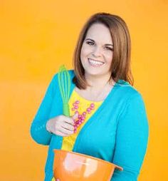 a woman holding a whisk and mixing bowl in front of an orange wall