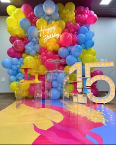 a room filled with lots of balloons and a happy birthday sign on the wall next to it