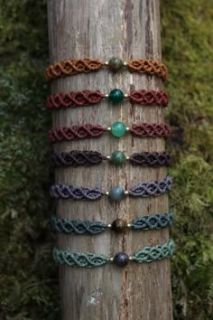 the bracelets are arranged on top of a wooden pole in front of some trees