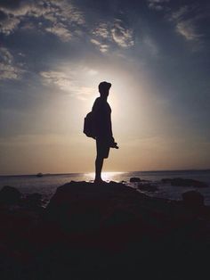 a person standing on top of a rock near the ocean