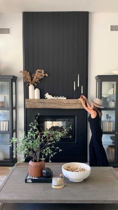 a woman standing in front of a fireplace with a bowl of food on the table