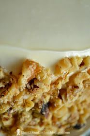 a close up of a piece of cake on a plate with white frosting and nuts