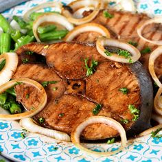 a plate topped with meat and onions on top of a blue and white table cloth